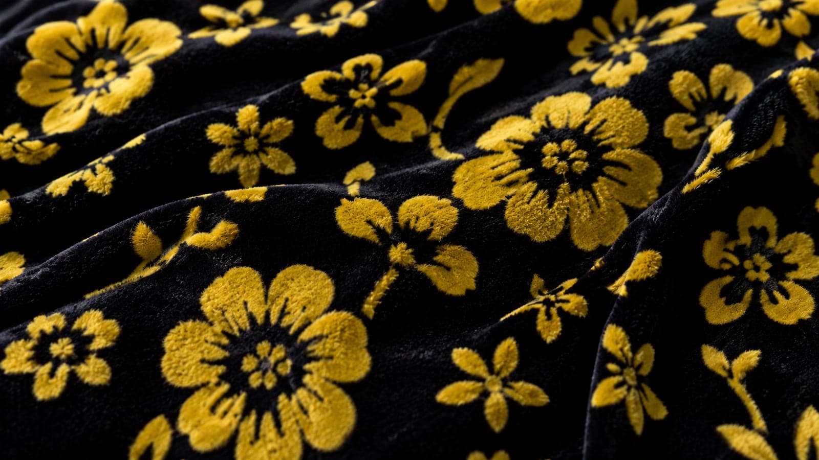 Tecido flocado com flores amarelas aplicadas sobre base preta