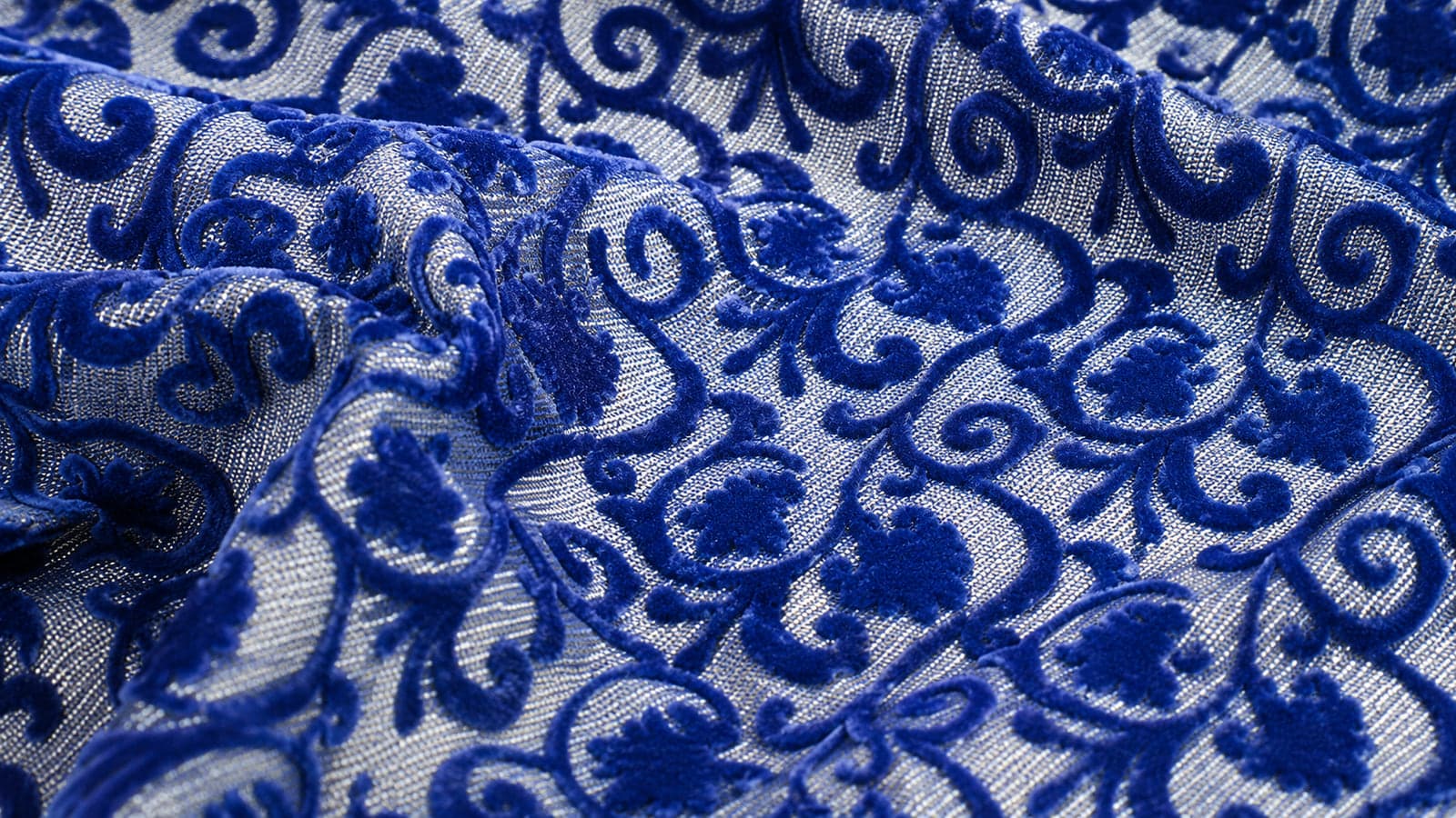 Tecido flocado com desenho floral em azul sobre base prateada